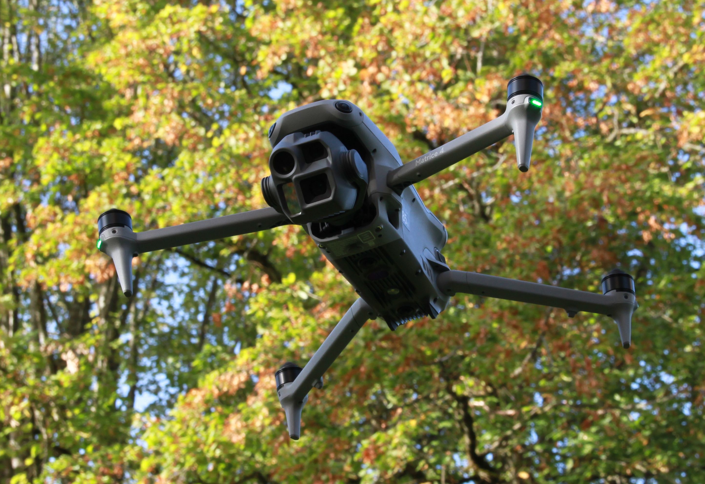 Vermessungsdrohne DJI Matrice 4E im Flug vor herbstlichen Bäumen